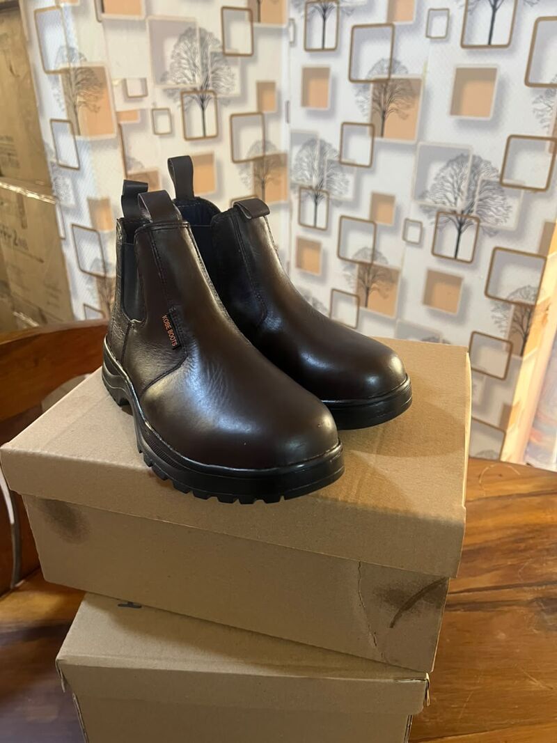 Pair of brown Chelsea boots standing on cardboard boxes